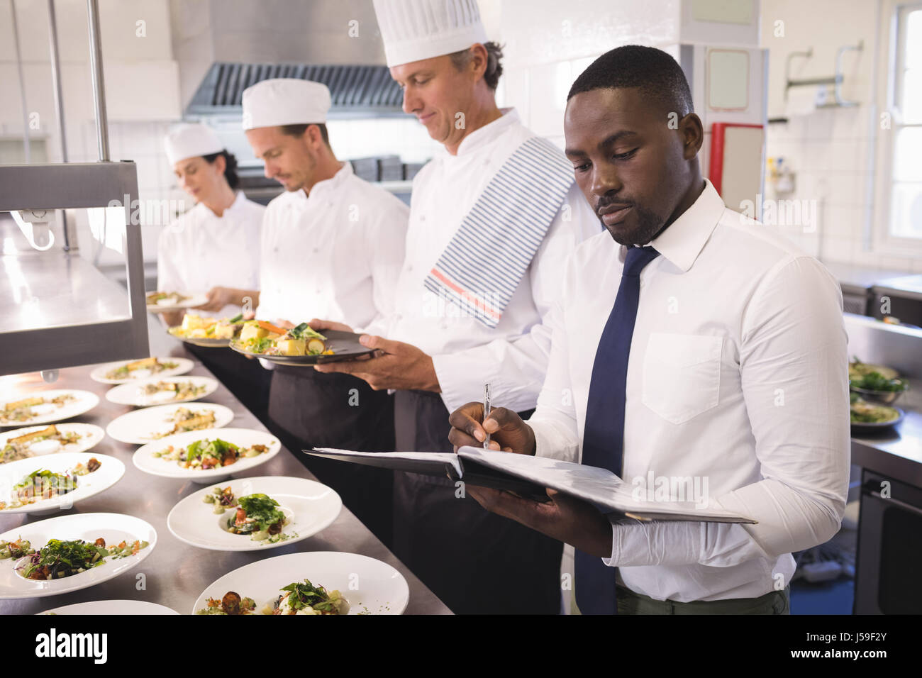 Restaurant manager with his kitchen staff in the commercial kitchen Stock Photo