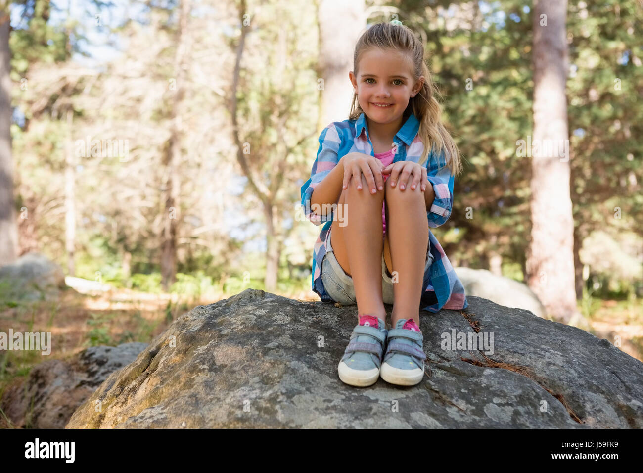 Portrait of smiling girl sitting on the rock in the forest Stock Photo ...