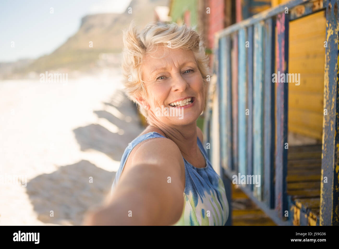 Portrait of smiling senior woman standing by hut at beach Stock Photo ...