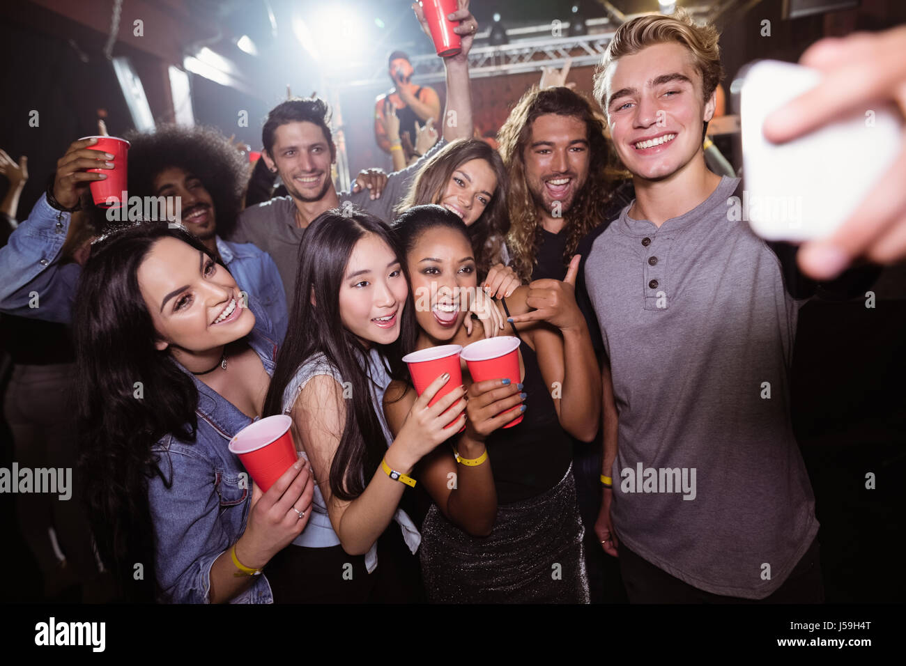 Happy friends taking selfie at popular music concert Stock Photo