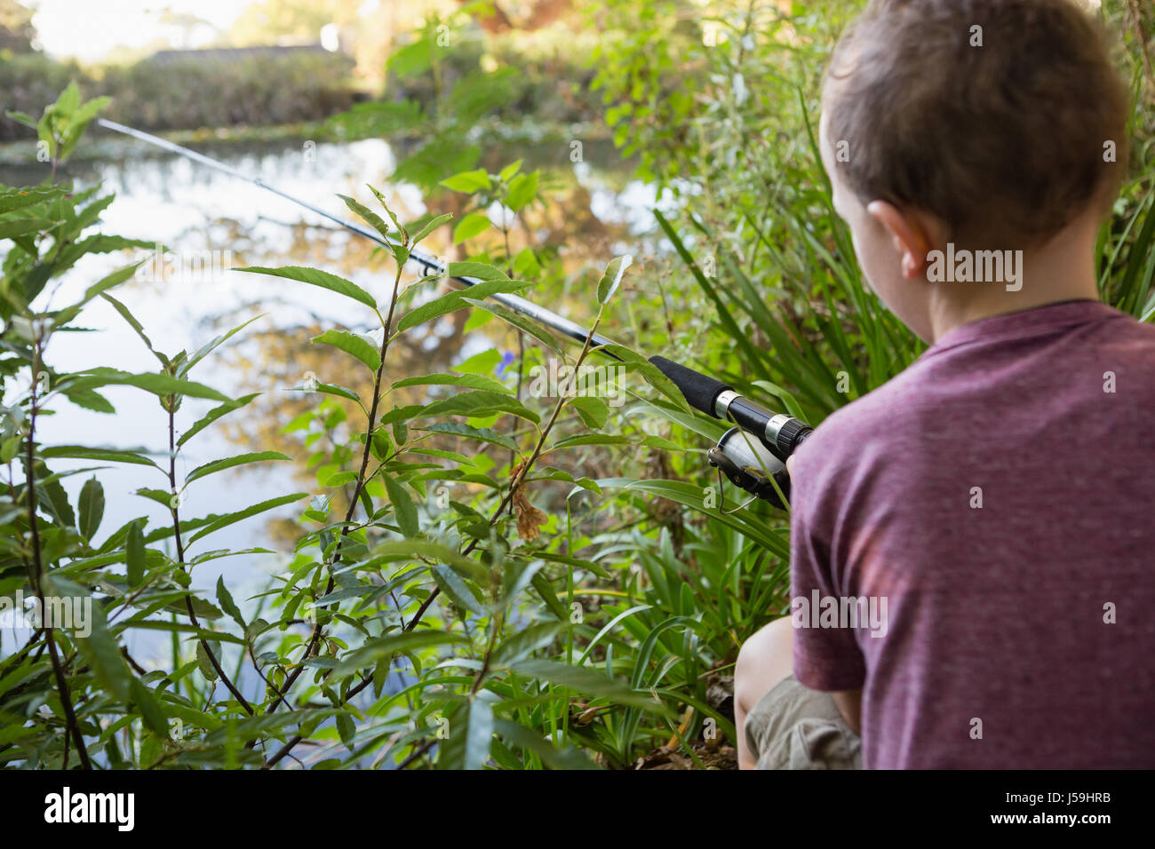 Rear view of boy fishing in the river in forest Stock Photo