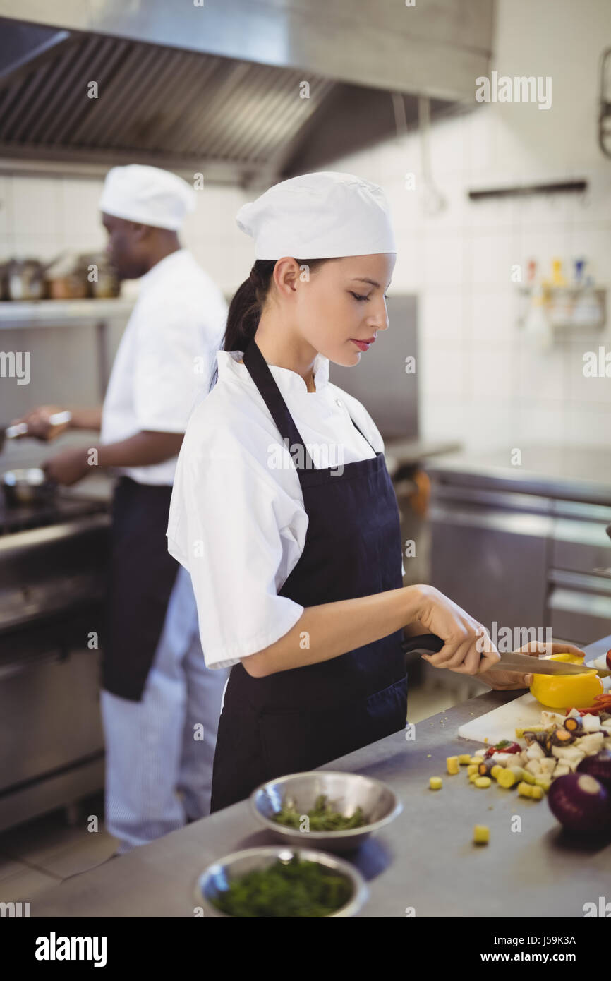 Female chef chopping vegetables on chopping board in the commercial