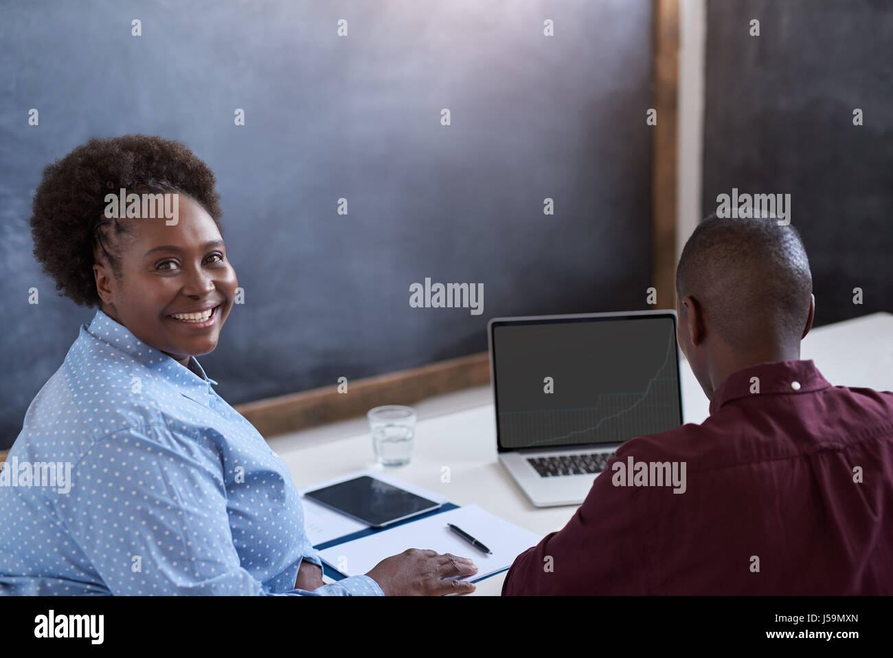 Smiling African businesswoman working with a colleague in an office ...