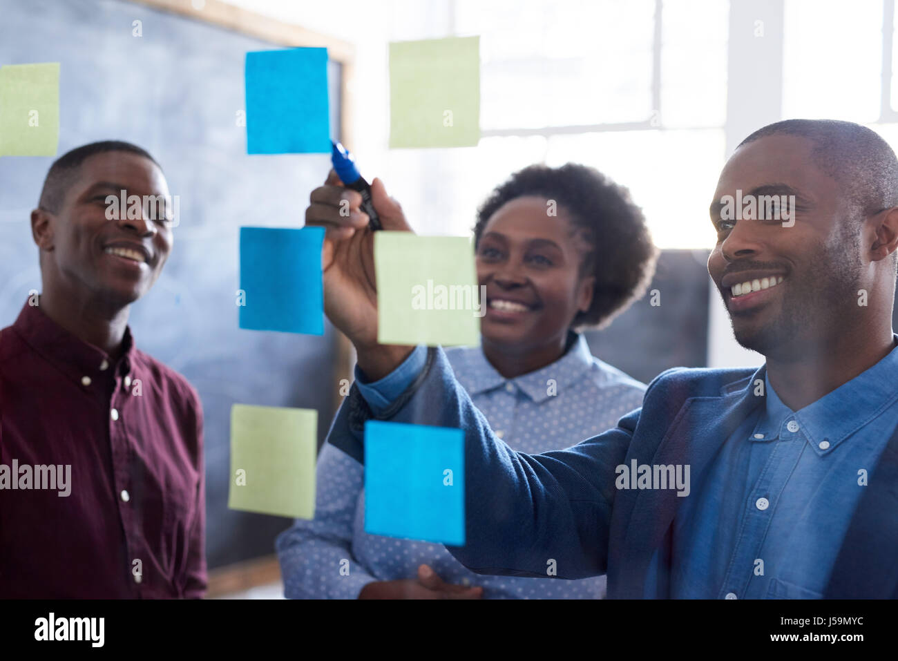 Positive African work colleagues brainstorming together in an office Stock Photo