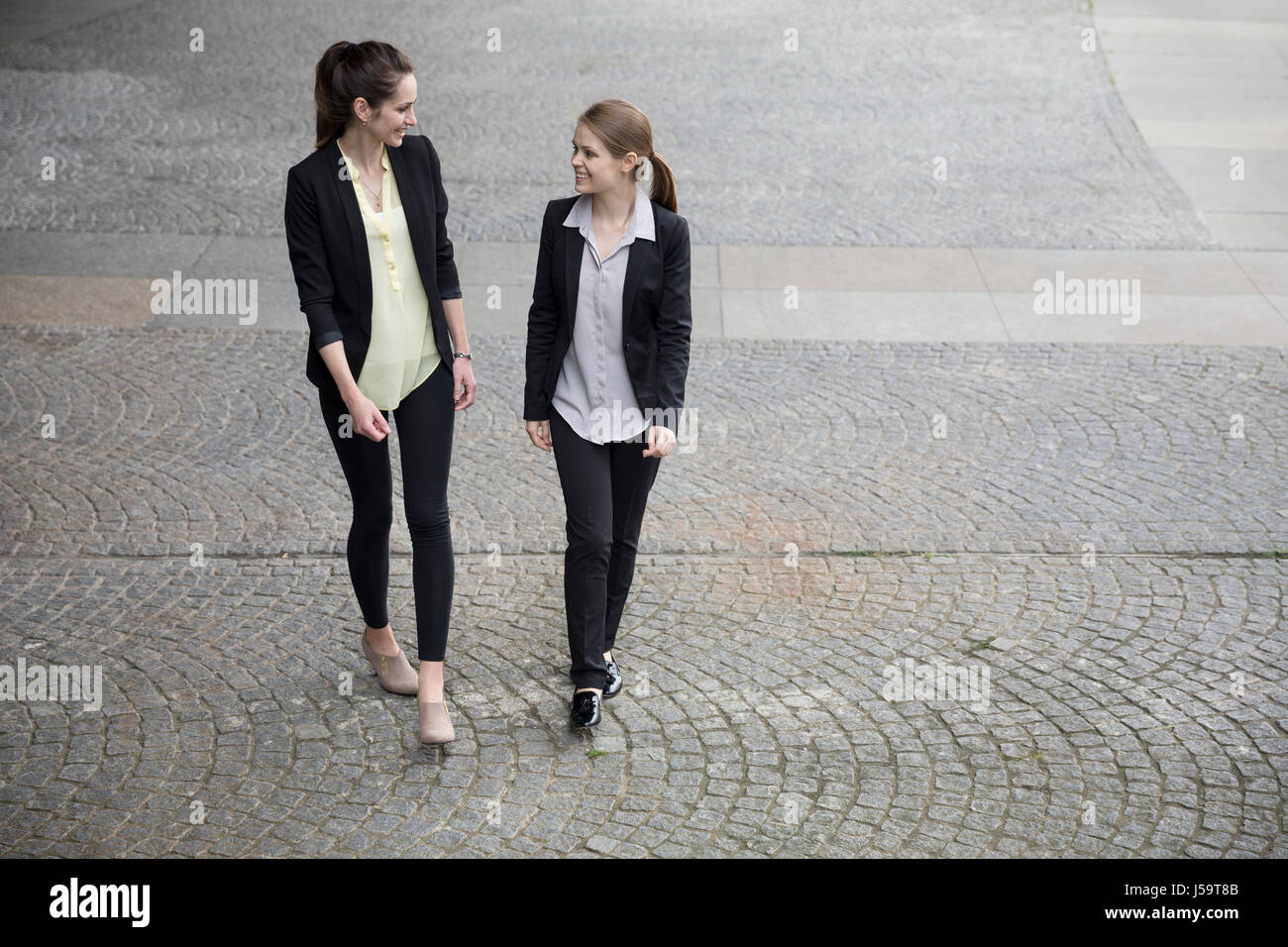 Elevated view of two caucasian business women talking outside modern office buidling. Stock Photo