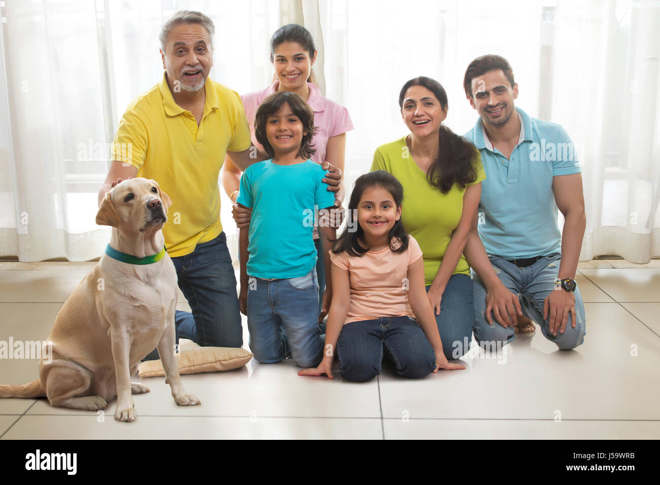 Portrait of multi-generation family with dog kneeling on wooden floor Stock Photo