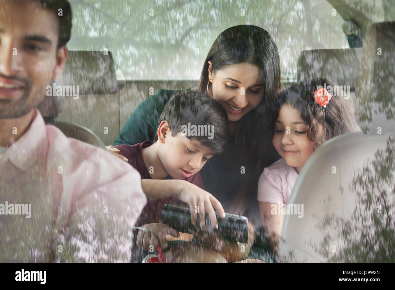 Happy family in car using digital tablet Stock Photo