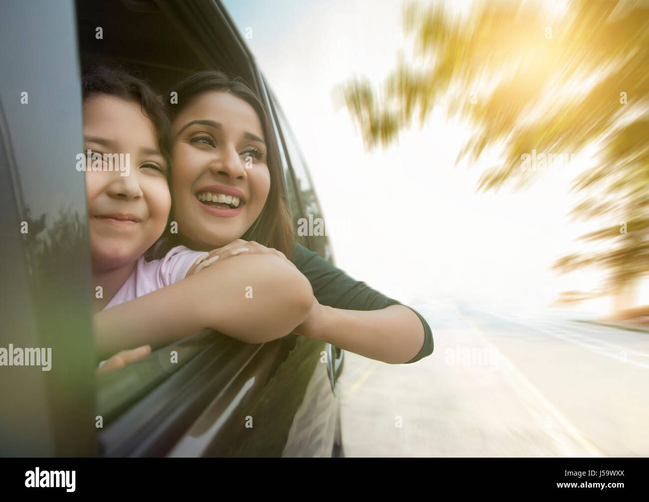 Happy mother and daughter looking out car window Stock Photo