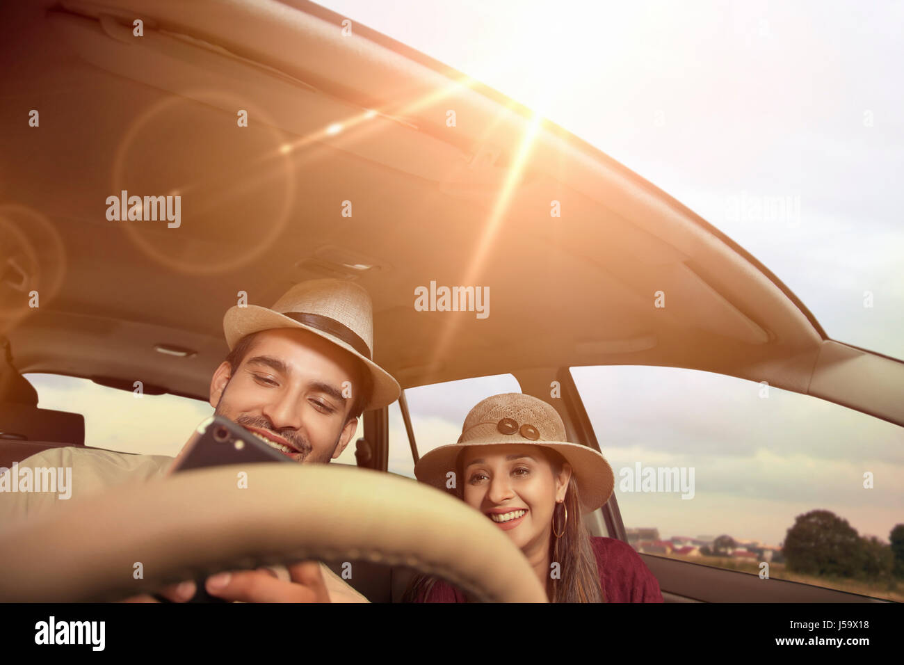 Young couple wearing hat riding in car Stock Photo