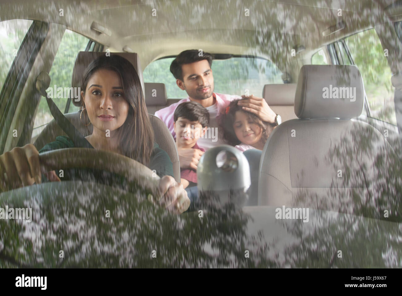 Mother driving car and her family sitting in back seat of car Stock Photo