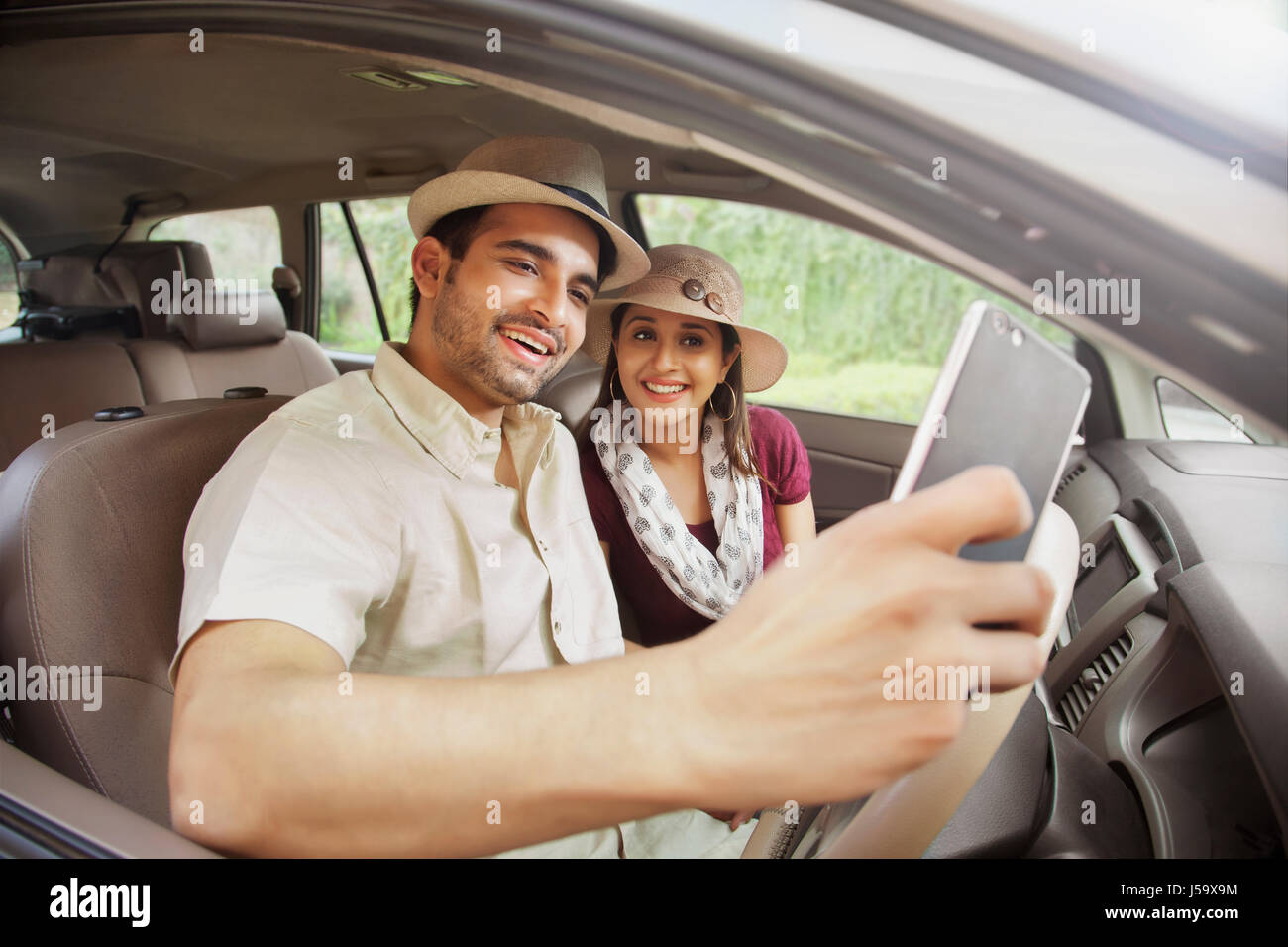 Couple wearing hat taking a selfie in car Stock Photo