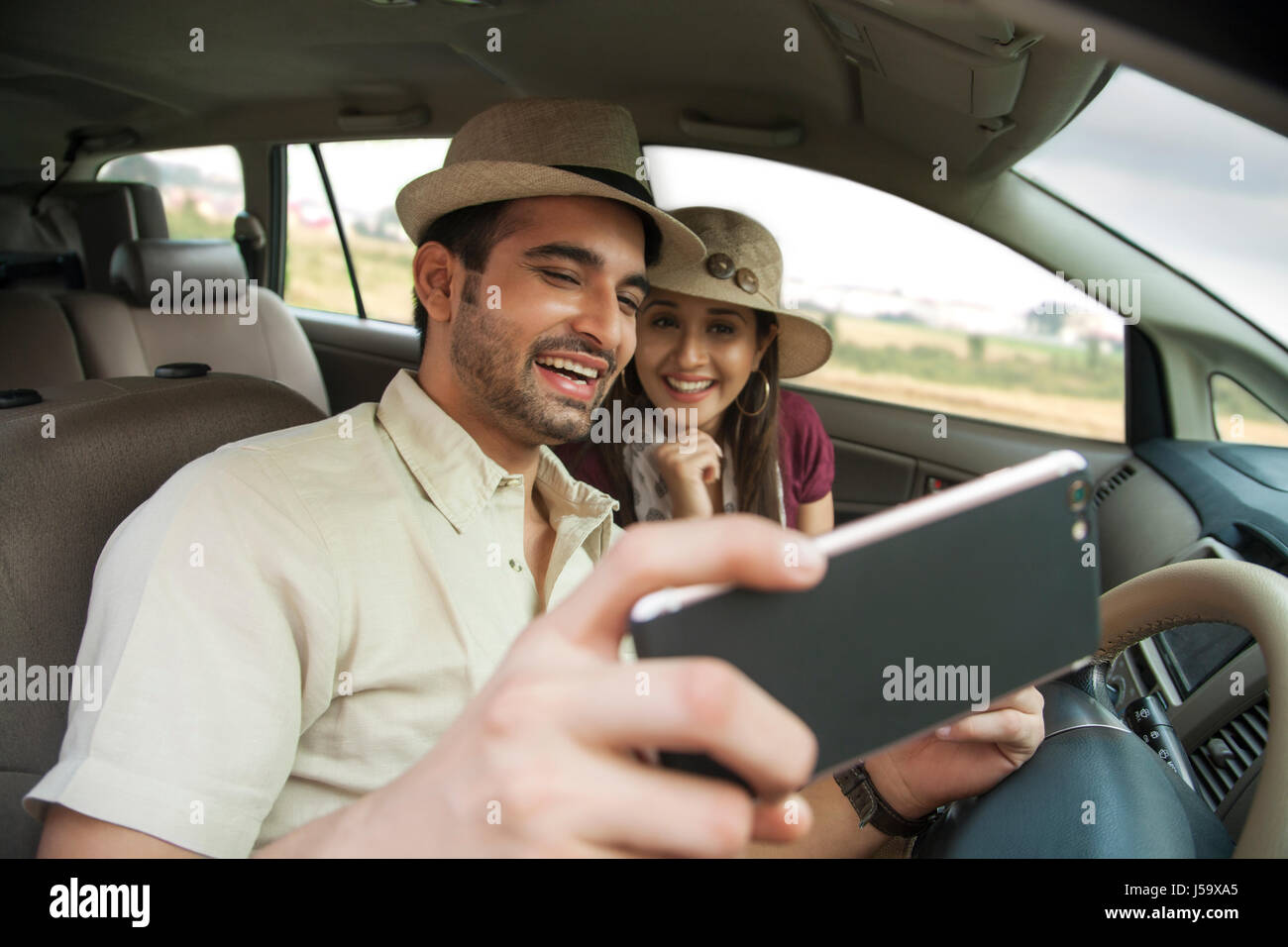 Happy young couple wearing hat taking a selfie in car Stock Photo