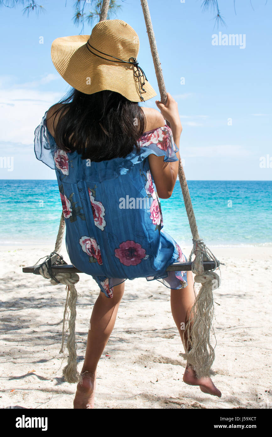 Girl sitting on a wooden swing on the beach. Summer holiday goals Stock Photo