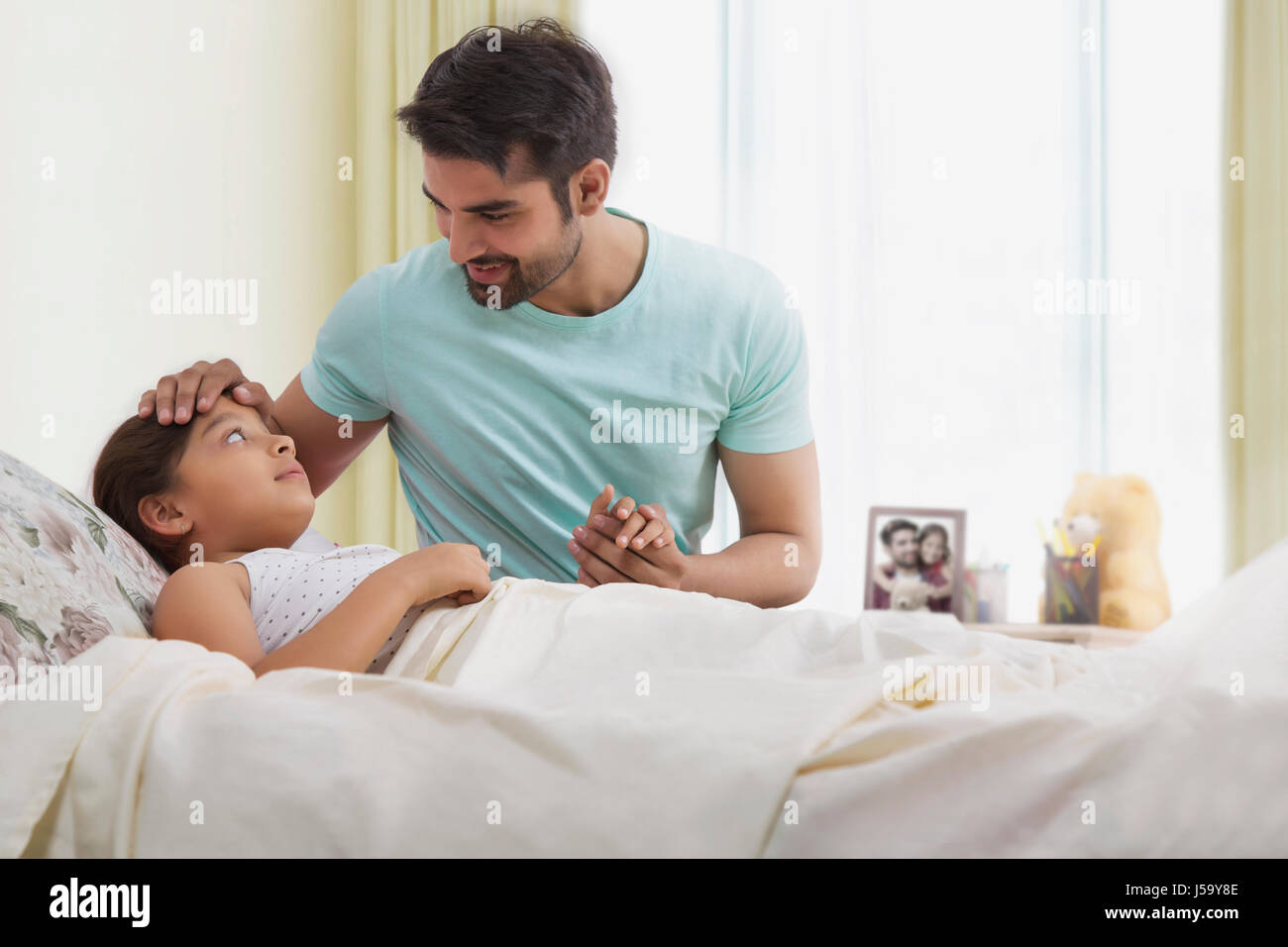 Father checking temperature of sick daughter Stock Photo