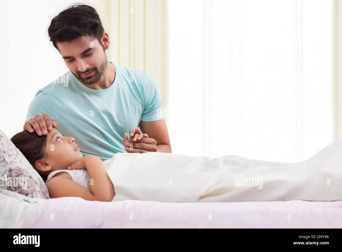 Father checking temperature of sick daughter Stock Photo