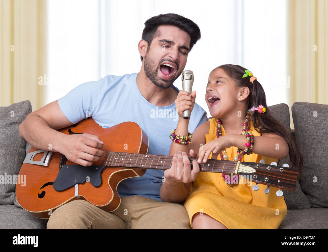 Father and daughter singing while playing guitar Stock Photo