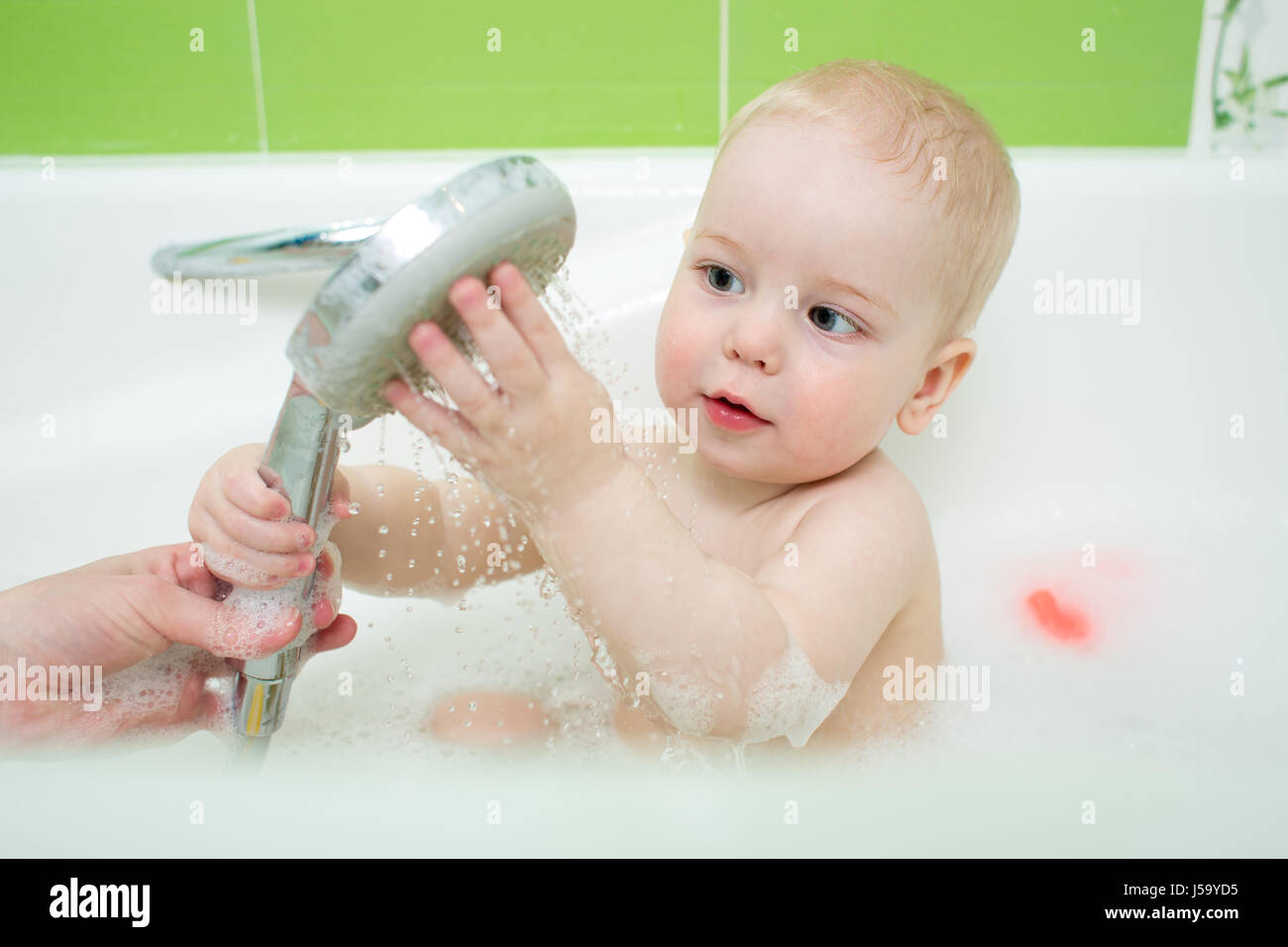 Happy funny baby showered and bathed in the bath. Stock Photo