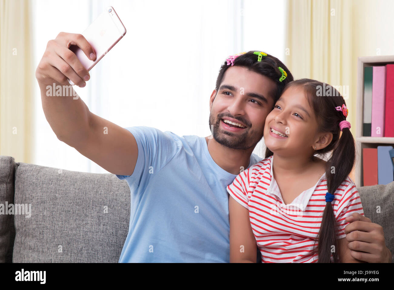Funny father wearing hair clips and daughter taking selfie Stock Photo