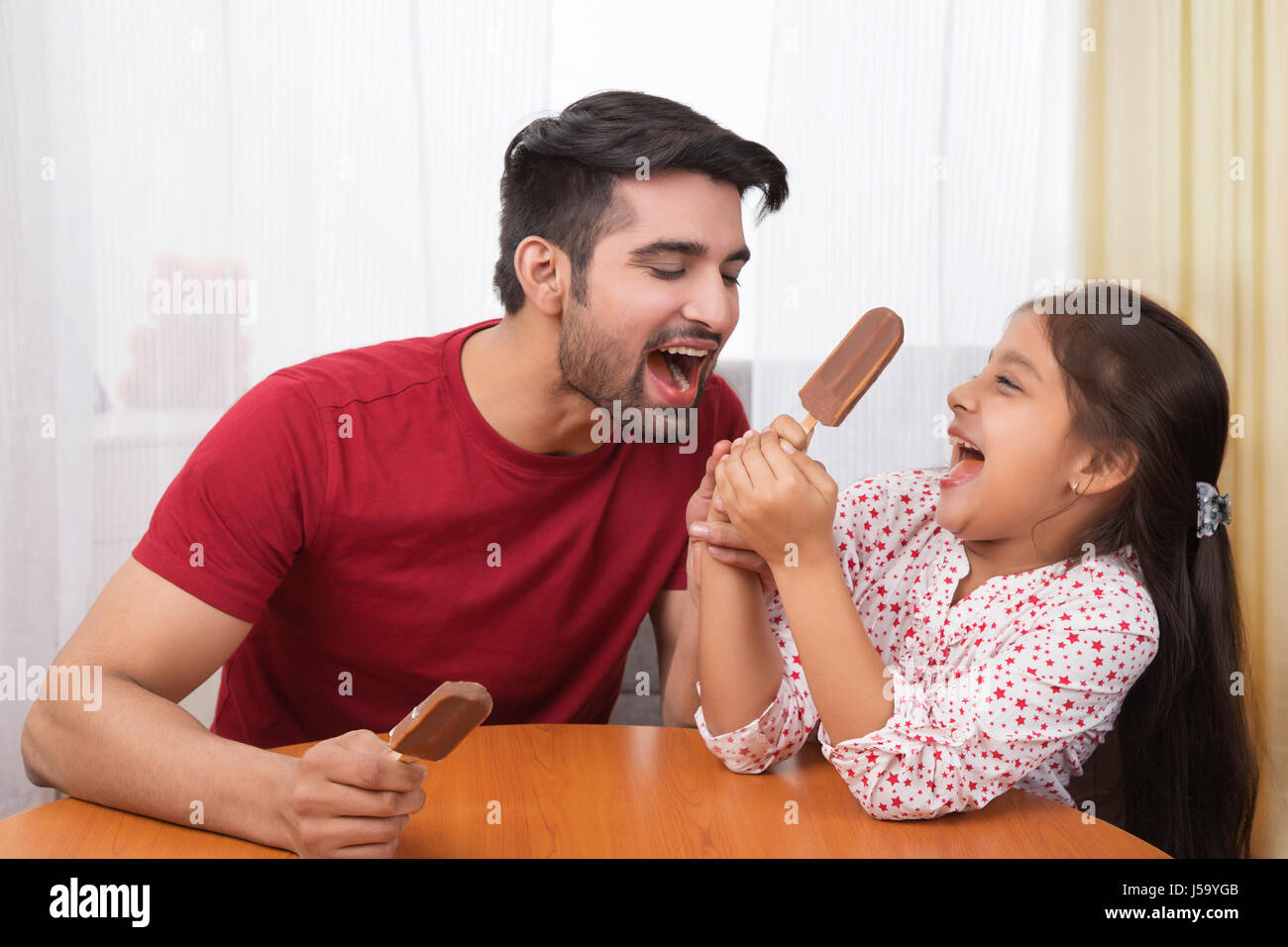 Father sharing ice cream with daughter Stock Photo