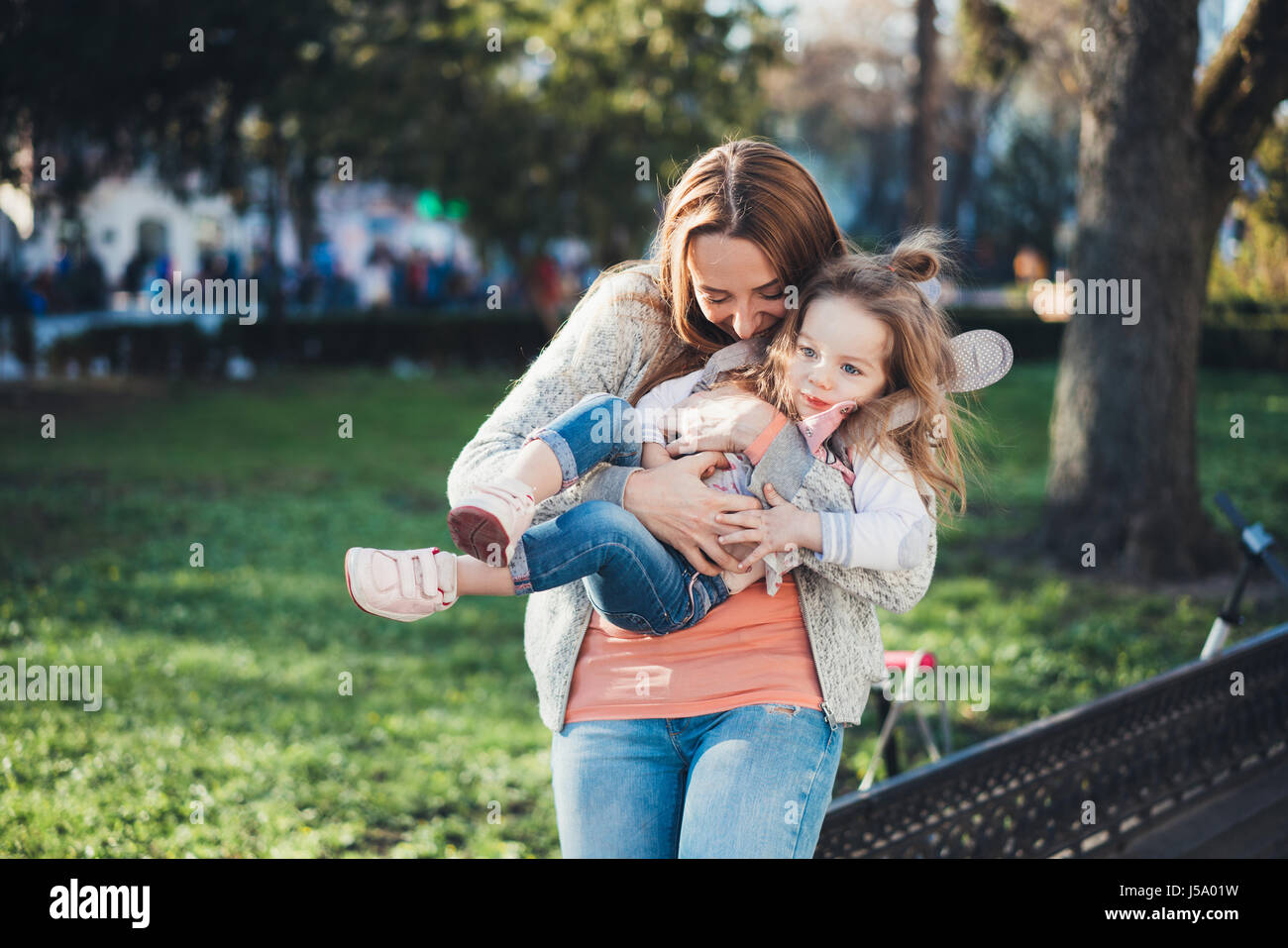 мама с дочкой на руках. две девушки обнимаются. фотосессия в парке мать и дочь белые платья. мама держит трёх летнего на руках. дочерью на руках девушка.
