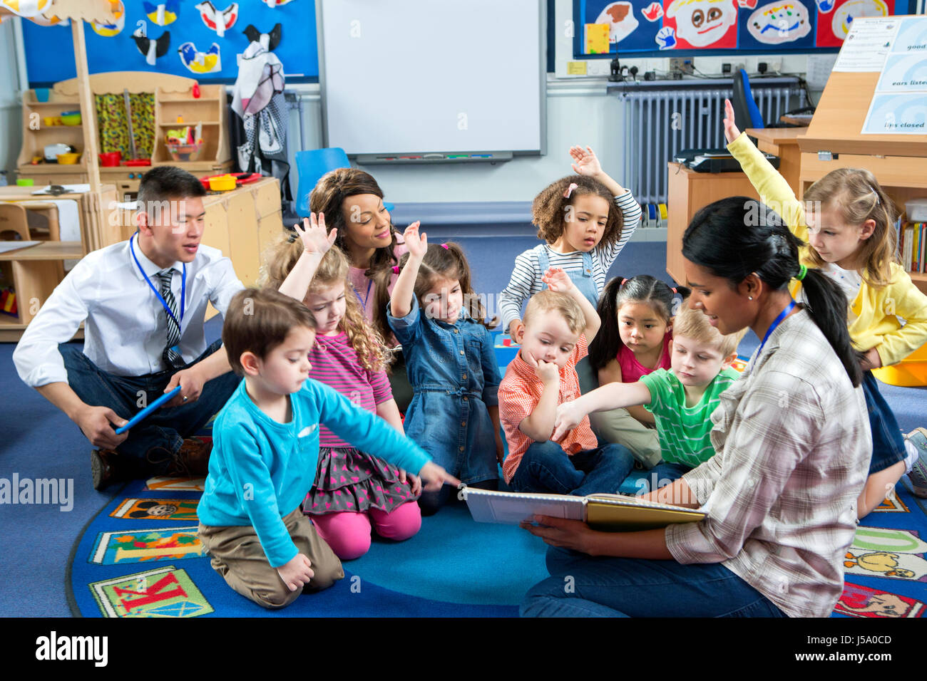Female teacher giving a lesson to nursery students. They are sitting on