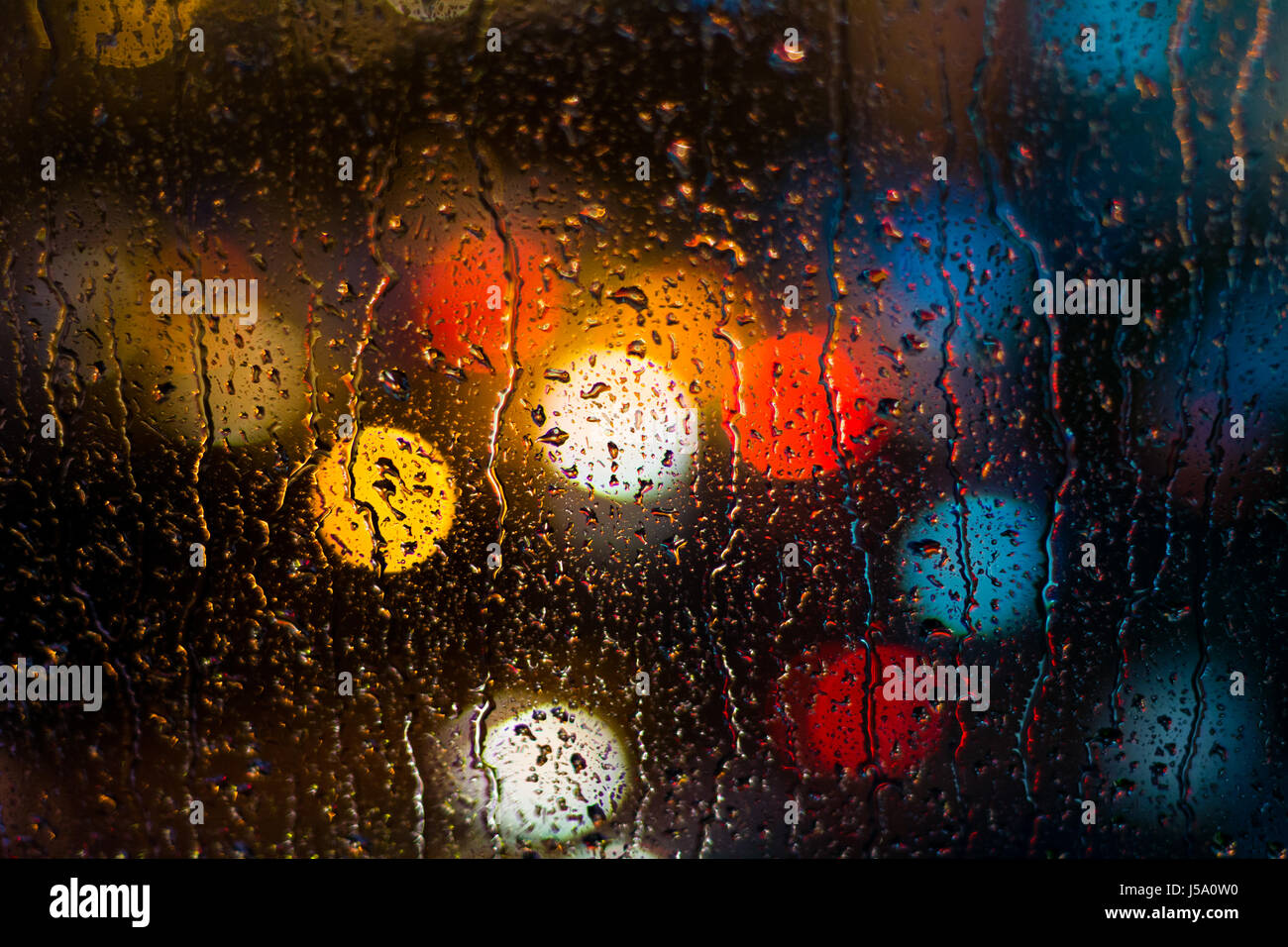 Defocused car light behind raindrops Stock Photo