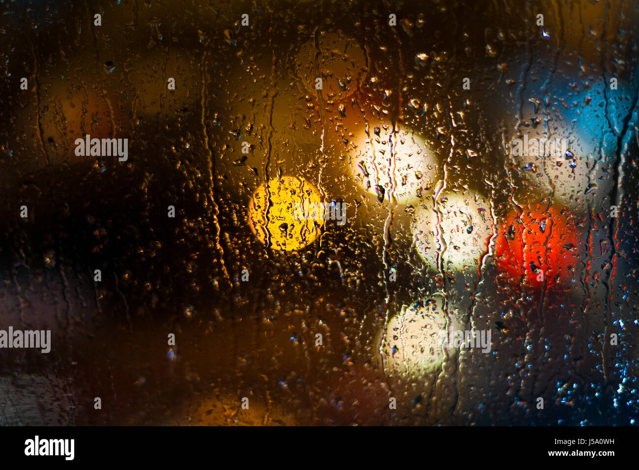 Defocused car light behind raindrops Stock Photo