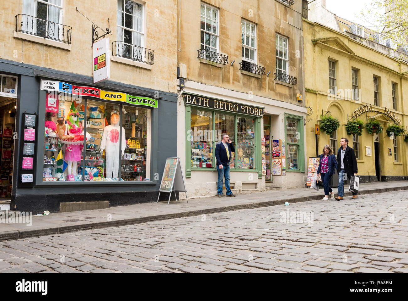 Bath Retro Store and Fancy dress shop with people walking next to them in Abbey Green, Bath, UK. Stock Photo