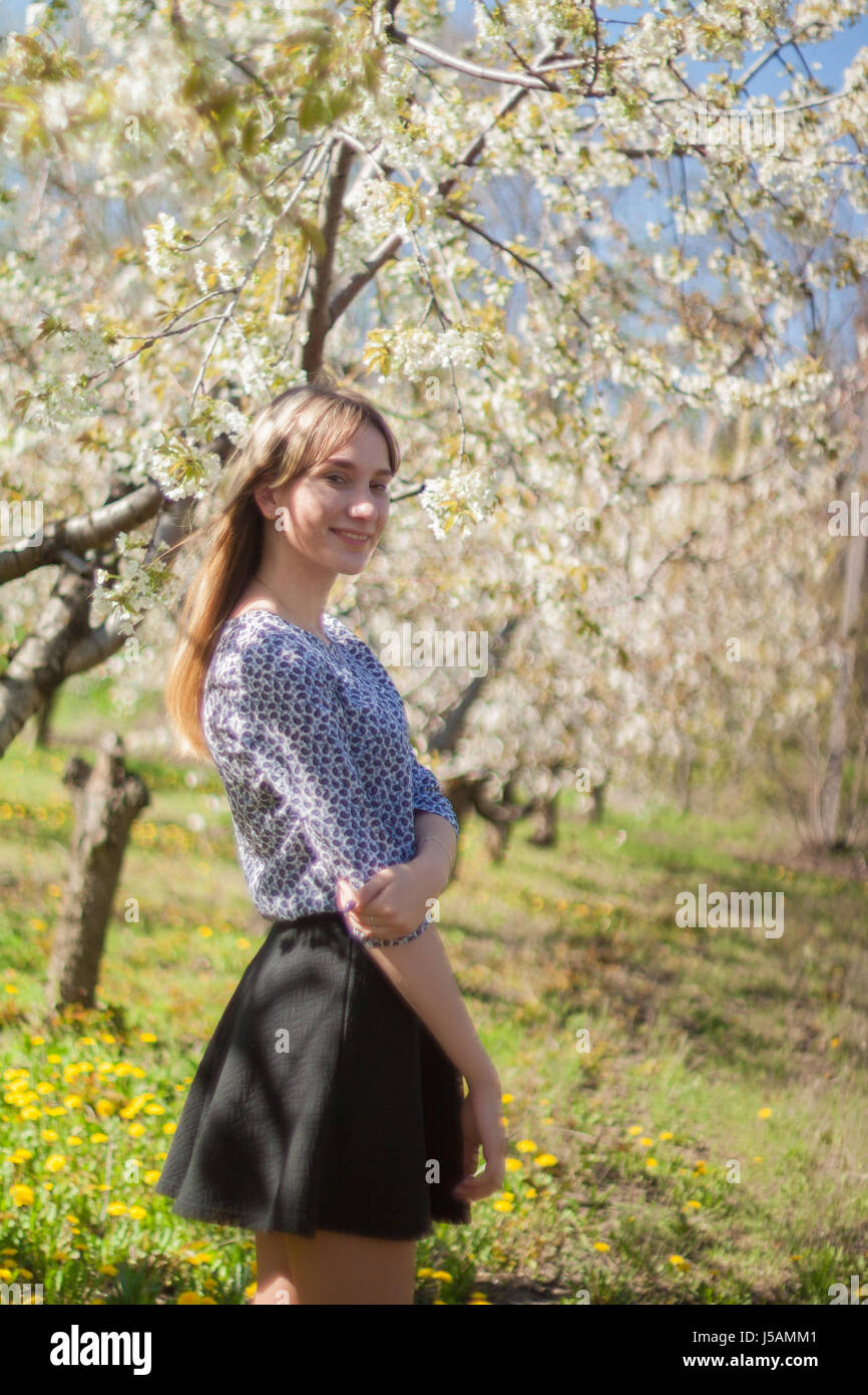 Portrait of a beautiful young girl in a blooming garden against a ...