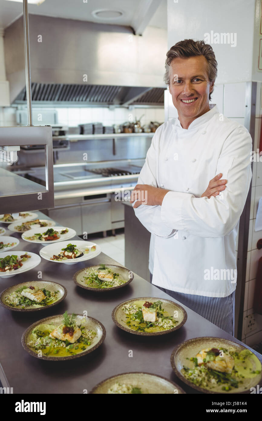 Portrait of happy chef with appetizer plates at order station in ...