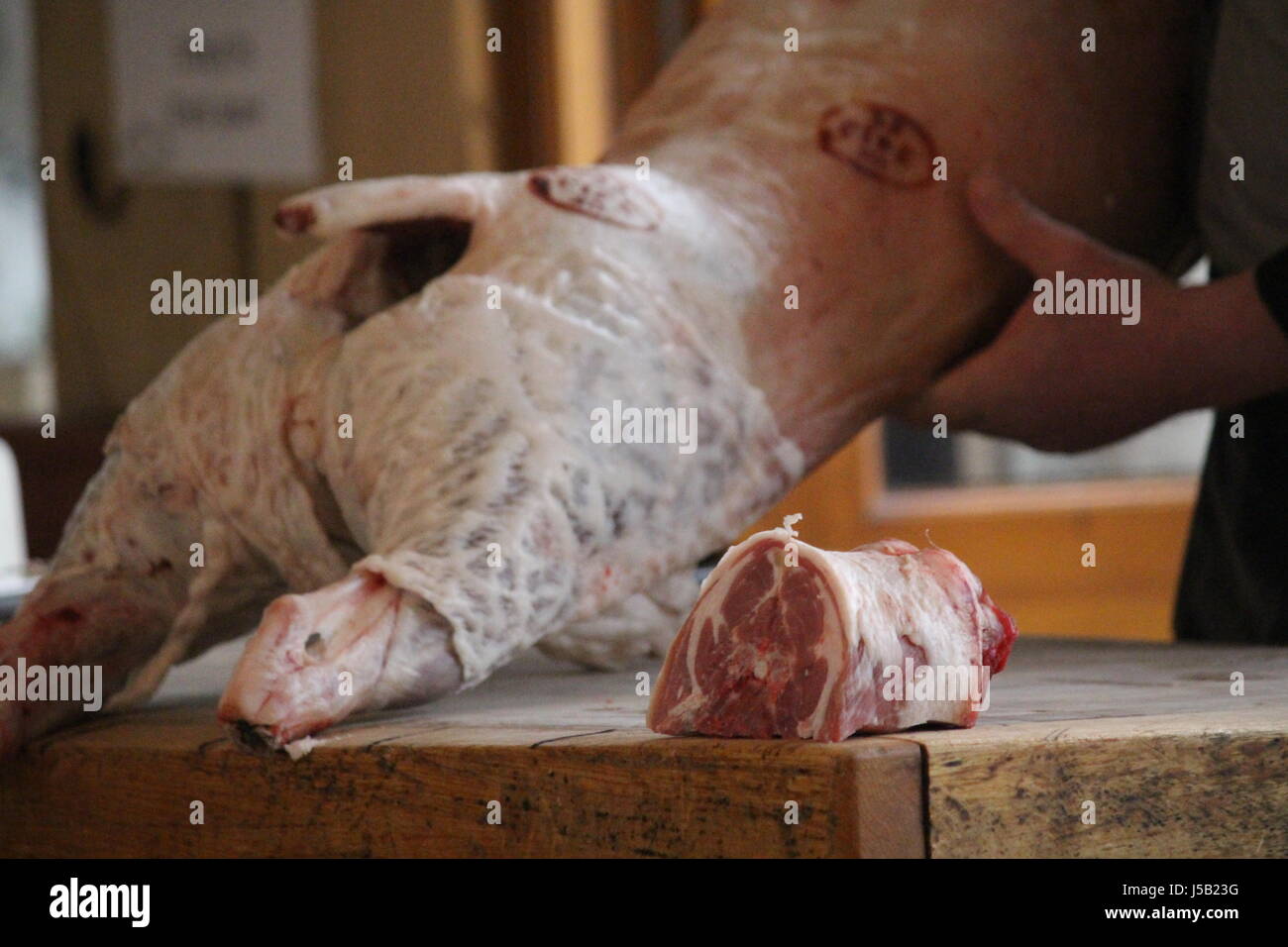 Butcher cutting up a lamb carcass on a butchers block Stock Photo