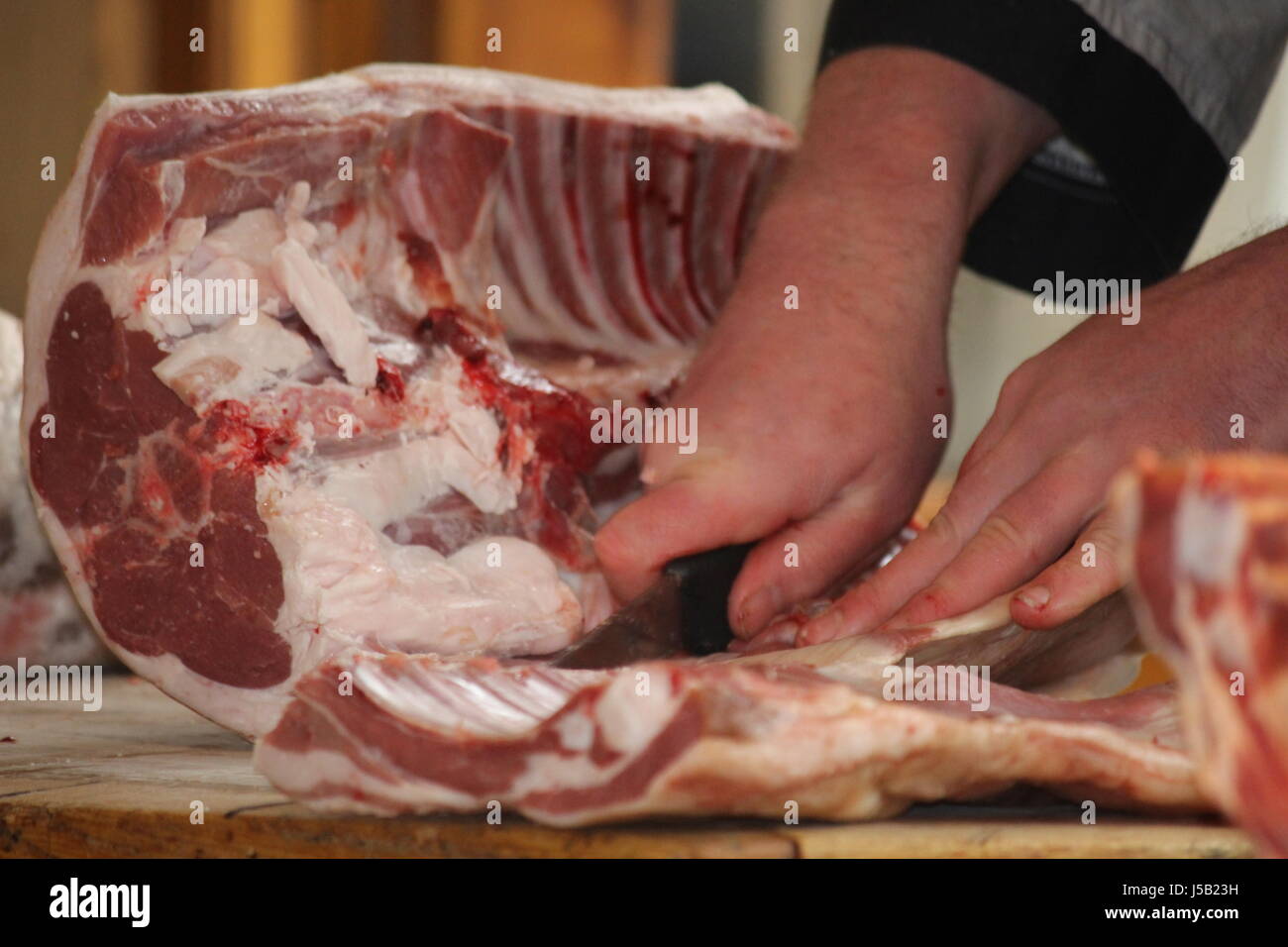 Butcher cutting up a lamb carcass on a butchers block Stock Photo