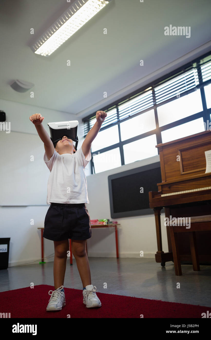 Low angel view of boy wearing virtual reality simulator gesturing while standing against piano at home Stock Photo