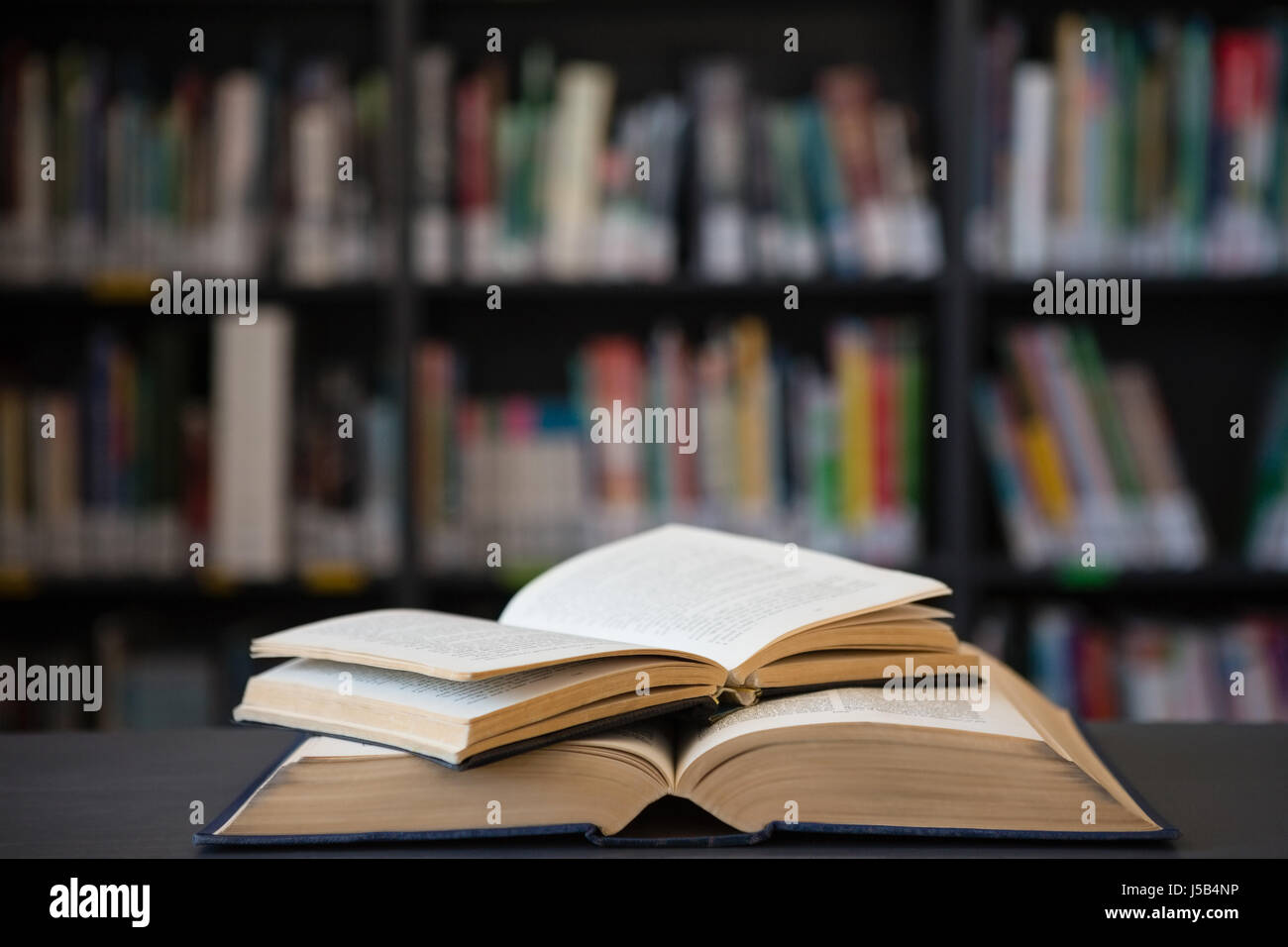 Close up of open books on table against shelf in library Stock Photo