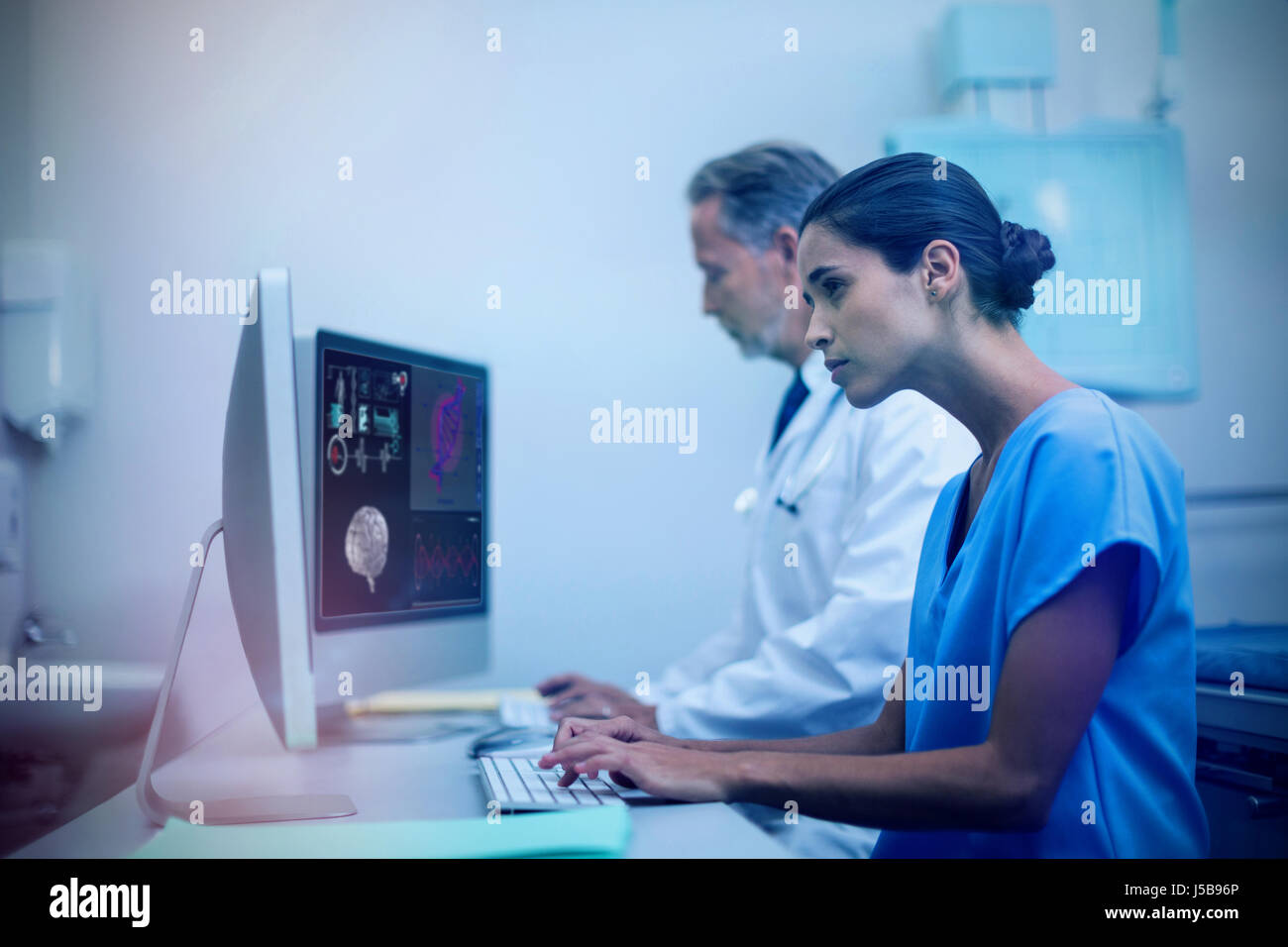 Human brain with various medical reports  against concentrated male doctor with nurse working on computer Stock Photo