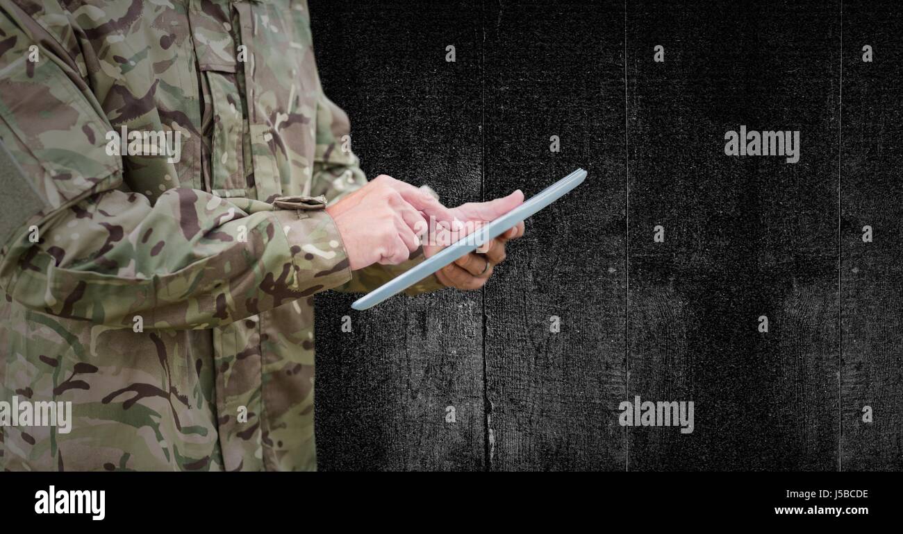 Digital composite of Soldier mid section with tablet against black wood panel Stock Photo