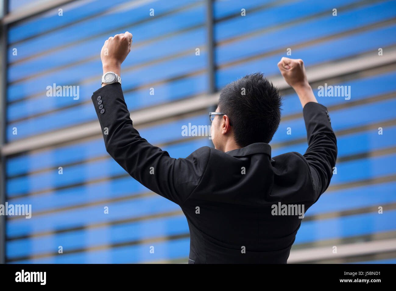 Chinese businessman outside office building with his arms raised ...