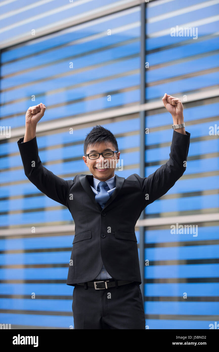 Chinese businessman outside office building with his arms raised ...