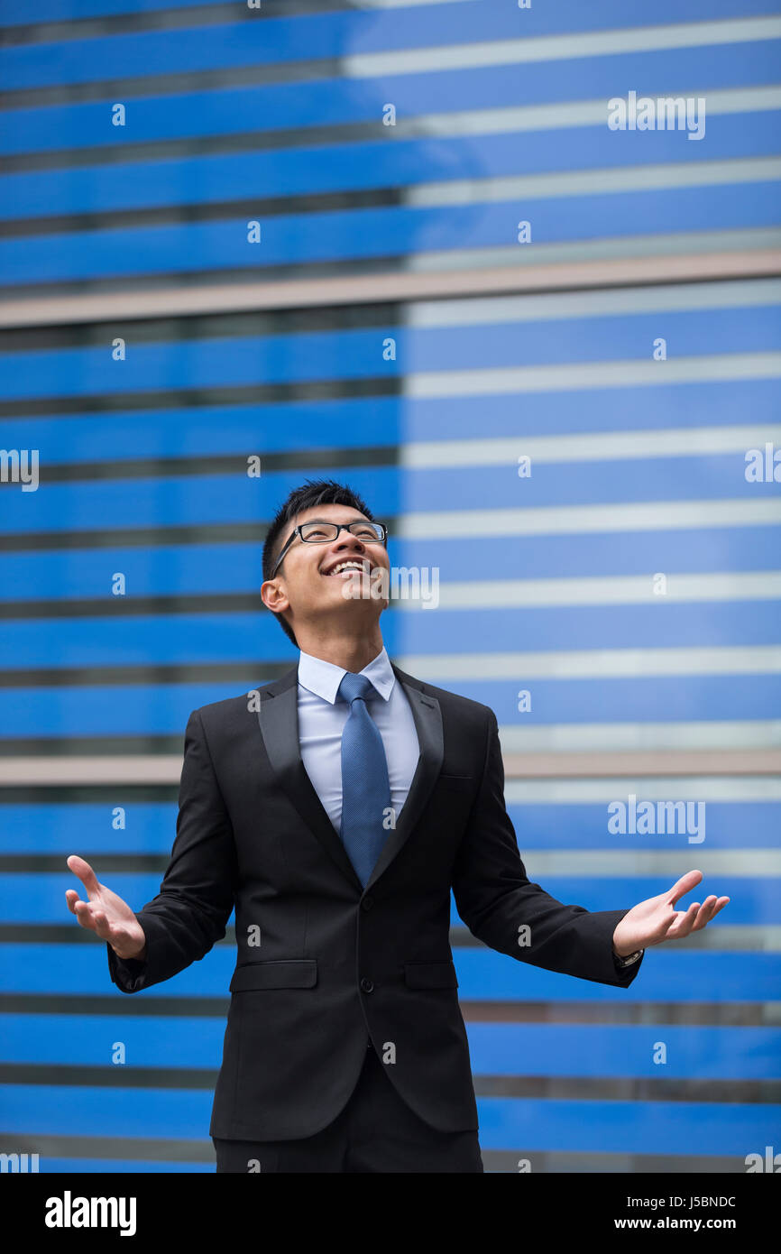Chinese businessman outside office building with his arms raised ...