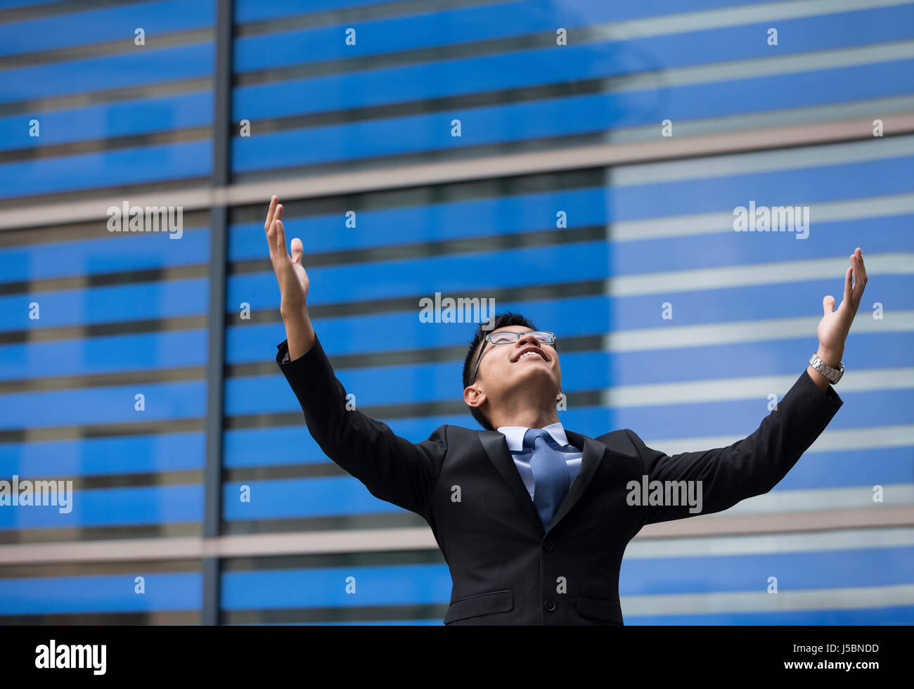 Chinese businessman outside office building with his arms raised ...