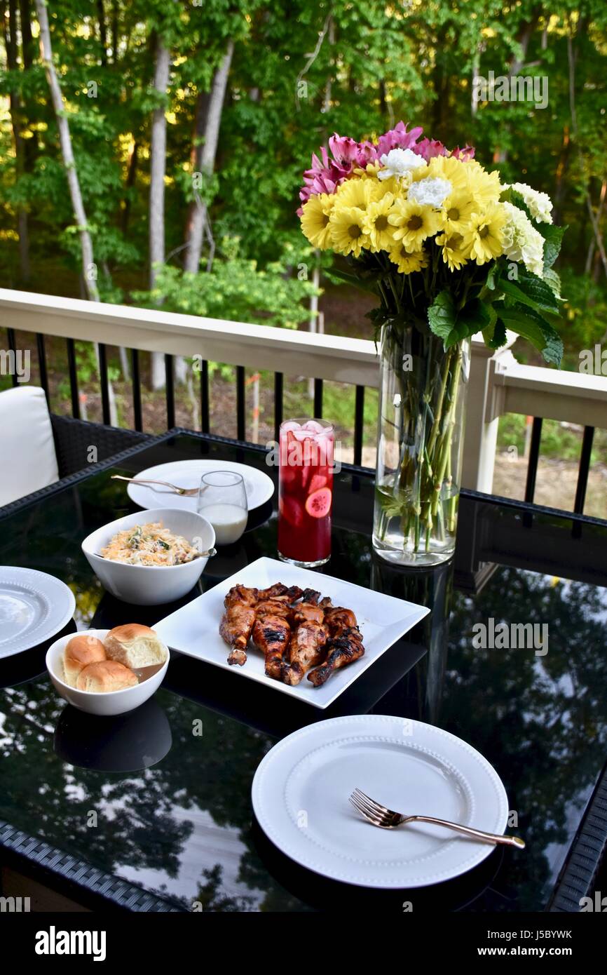 Outdoor dining with BBQ chicken drumsticks, dinner rolls, pasta salad, and iced tea Stock Photo