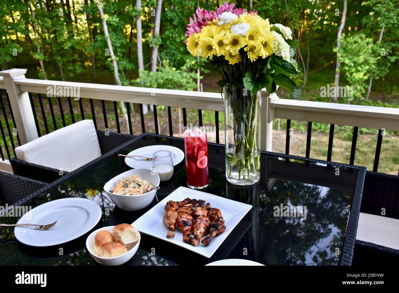 Outdoor dining with BBQ chicken drumsticks, dinner rolls, pasta salad, and iced tea Stock Photo
