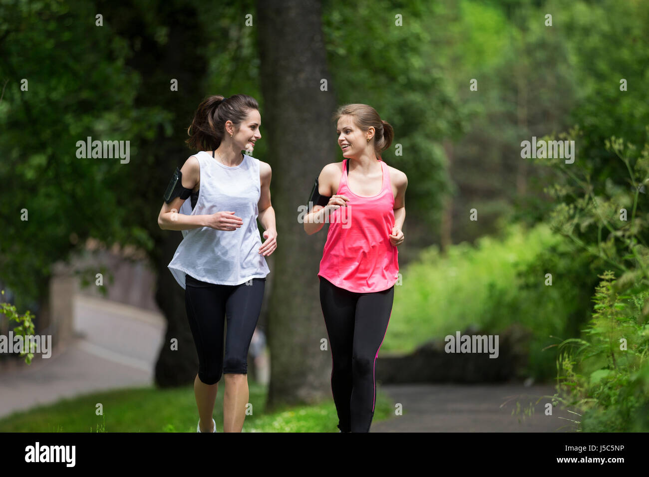 Two athletic woman running outdoors. Action and healthy lifestyle concept. Stock Photo