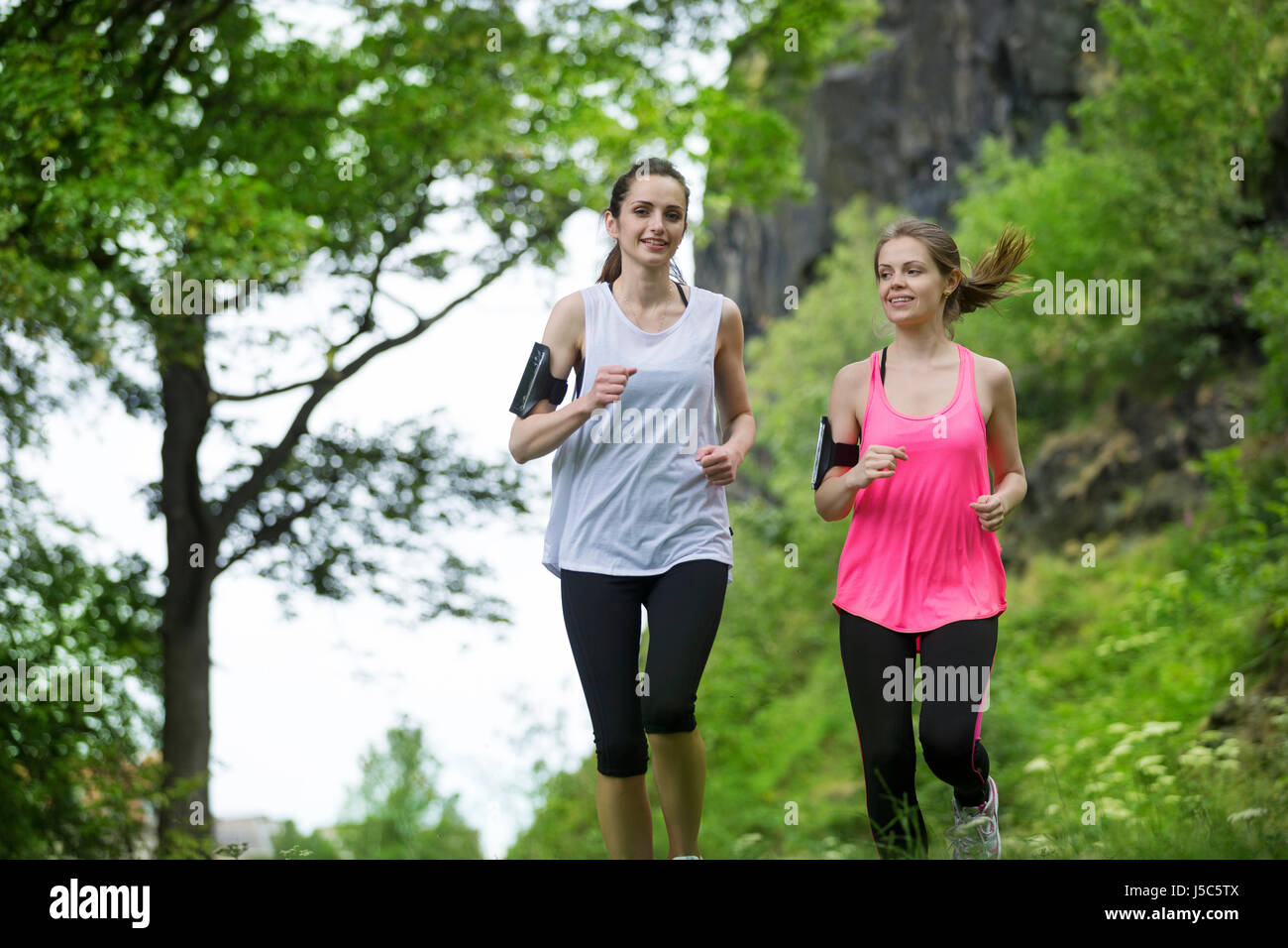 Two athletic women running outdoors. Action and healthy lifestyle concept. Stock Photo
