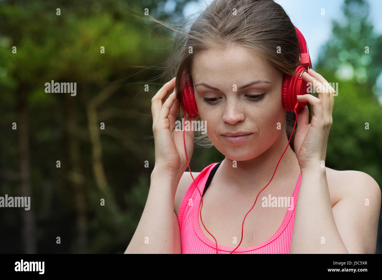 Active woman listening to music on her headphones as she exercises outside. Action and healthy lifestyle concept. Stock Photo