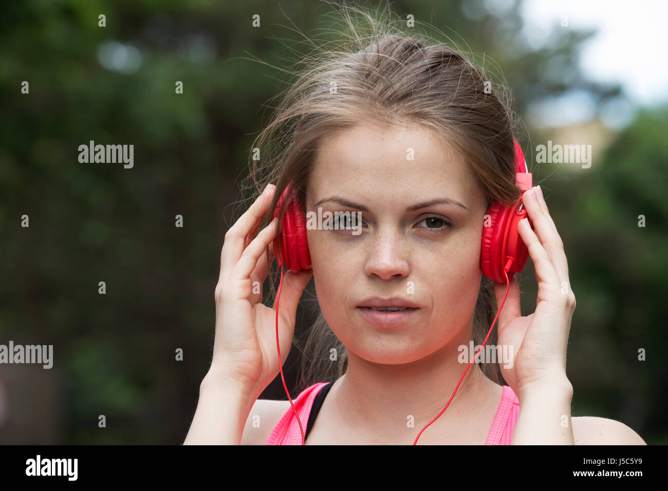 Active woman listening to music on her headphones as she exercises outside. Action and healthy lifestyle concept. Stock Photo