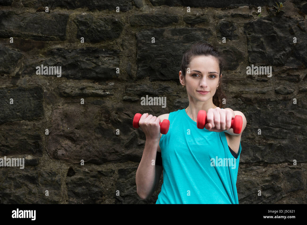 Athletic woman athletic using dumbbells. Action and healthy lifestyle concept. Stock Photo