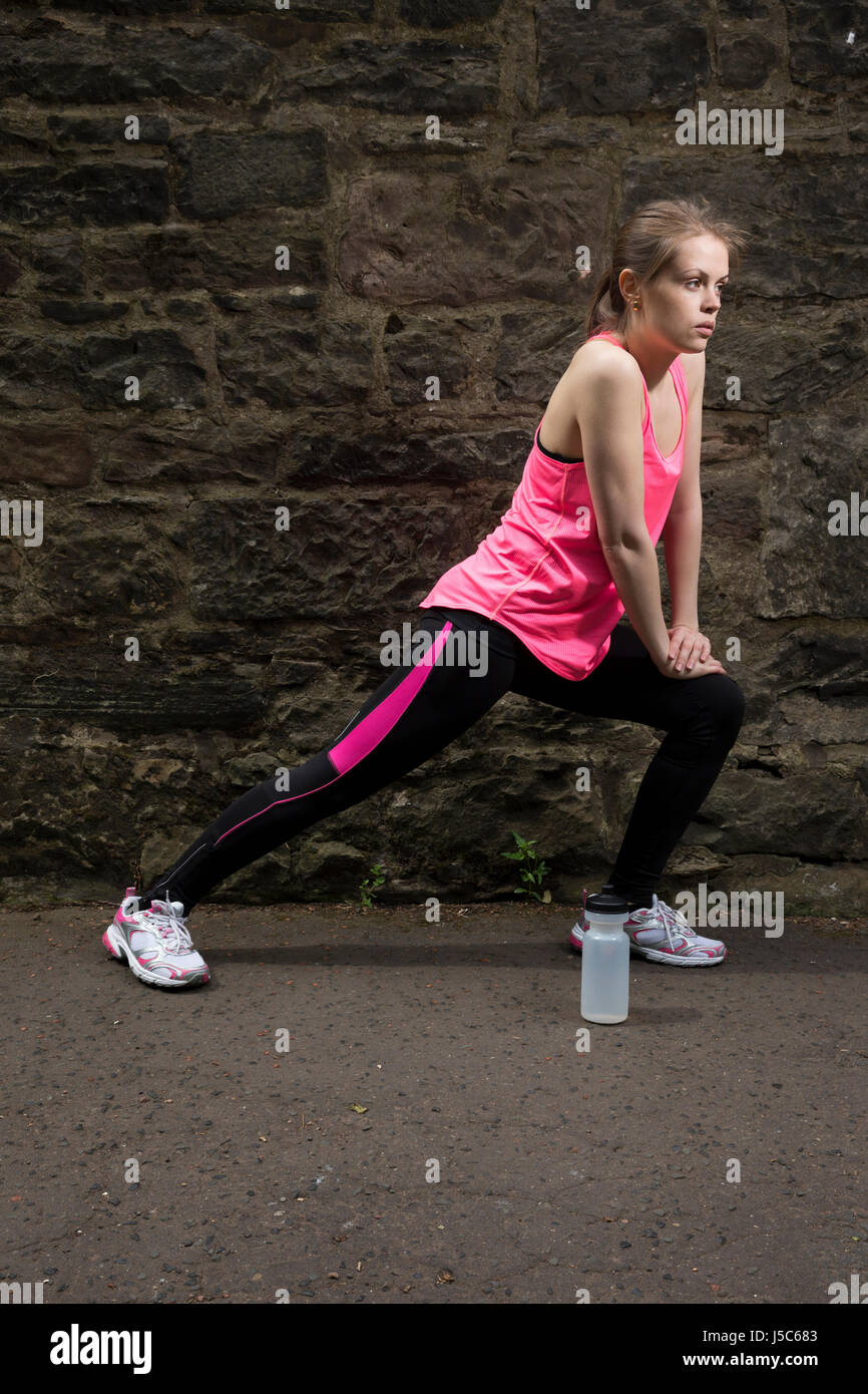 Athletic woman stretching before or after training. Action and healthy lifestyle concept. Stock Photo
