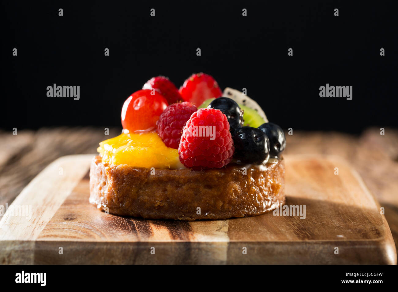 Fresh Fruit Flan sitting on a rustic wooden table. Stock Photo