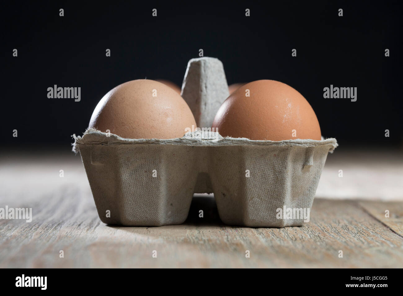 Carton of Farm fresh eggs sitting on rustic table. Stock Photo